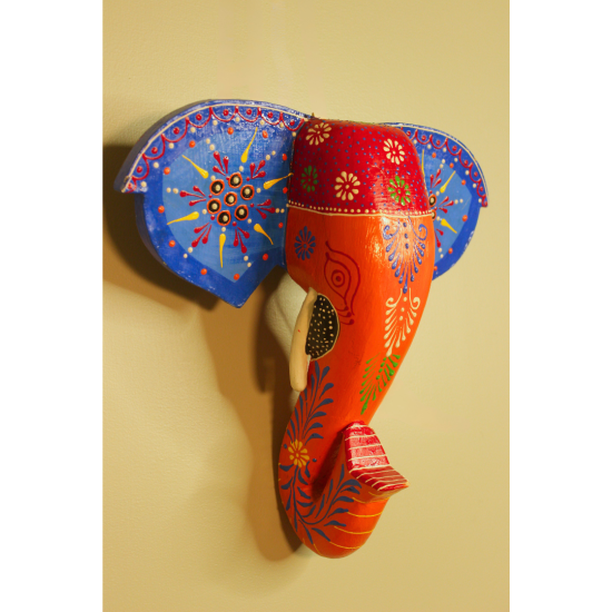 Hand-Painted Wooden Elephant Face Wall Decor in Blue and Orange – Indune Hand-painted wooden elephant face wall decor in blue and orange placed above a traditional Indian decor setup