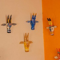 White base cow face wall decor with yellow and brown handpainted detailing in traditional Indian folk art style.