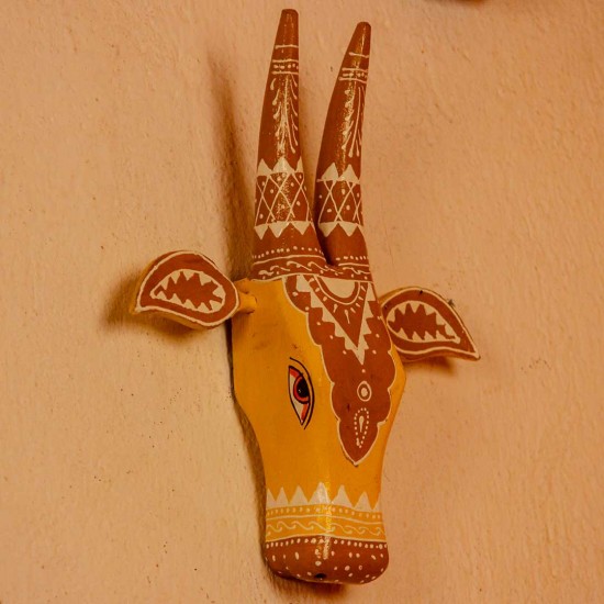 White base cow face wall decor with yellow and brown handpainted detailing in traditional Indian folk art style.