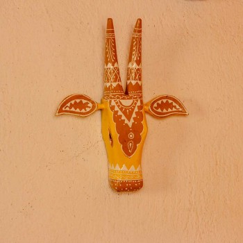 White base cow face wall decor with yellow and brown handpainted detailing in traditional Indian folk art style.