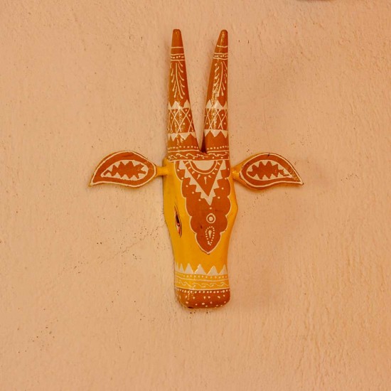 White base cow face wall decor with yellow and brown handpainted detailing in traditional Indian folk art style.
