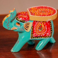 Small handpainted teal green elephant figurine with vibrant red and yellow detailing, designed in traditional Indian folk art style.