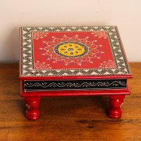 Wooden chowki hand painted in red with a mandala centrepiece and black-and-white geometric border, standing on four short carved legs.