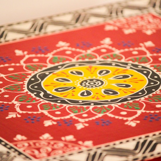 Wooden chowki hand painted in red with a mandala centrepiece and black-and-white geometric border, standing on four short carved legs.