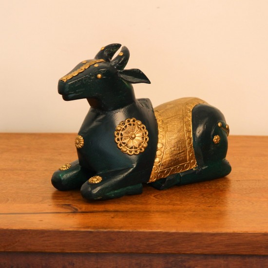 Deep green wooden Nandi figurine with embossed brass work placed on a wooden table as a pooja or console accent