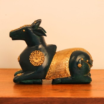 Green Nandi Figurine with Embossed Brass Styled on Table Deep green wooden Nandi figurine with embossed brass work placed on a wooden table as a pooja or console accent