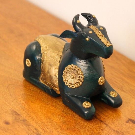 Deep green wooden Nandi figurine with embossed brass work placed on a wooden table as a pooja or console accent