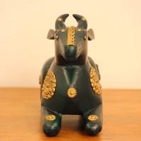 Deep green wooden Nandi figurine with embossed brass work placed on a wooden table as a pooja or console accent