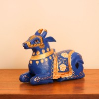Blue Nandi Figurine with Golden Finish Styled on Table Cobalt blue wooden Nandi figurine with gold painted detailing placed on a wooden table as a pooja or console accent.