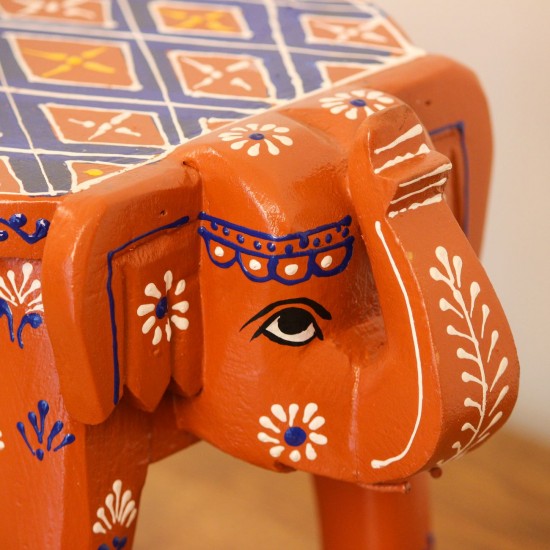 Hand Painted Burnt Orange Elephant Stool Styled on Table Hand-painted burnt orange-brown wooden elephant stool placed on a wooden table as a side stool or display stand.
