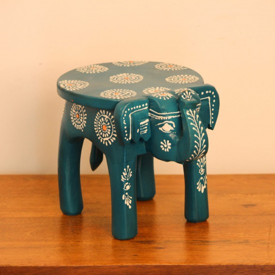 Teal blue hand-painted wooden elephant stool placed on a wooden table as a side stool or display stand.