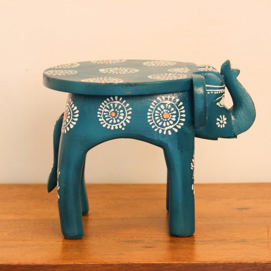 Teal blue hand-painted wooden elephant stool placed on a wooden table as a side stool or display stand.