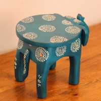 Teal blue hand-painted wooden elephant stool placed on a wooden table as a side stool or display stand.
