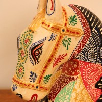 Hand Painted Patchwork Horse Head Decor Styled on Table Hand-painted patchwork wooden horse head with a cream face placed on a wooden table as a colourful tabletop accent.