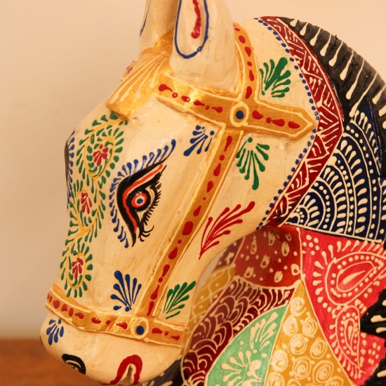 Hand Painted Patchwork Horse Head Decor Styled on Table Hand-painted patchwork wooden horse head with a cream face placed on a wooden table as a colourful tabletop accent.