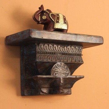 Distressed blue carved wooden shelf mounted on a warm wall with a décor piece on top