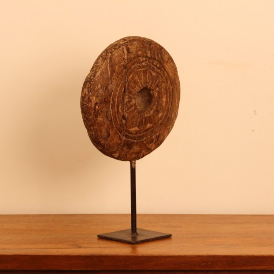 Antique Wooden Wheel Decor Genuine antique wooden wheel with a hand-carved radiating floral pattern around a central hole, mounted upright on a stand as a tabletop decor piece.