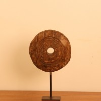Antique Wooden Wheel Decor Genuine antique wooden wheel with a hand-carved radiating floral pattern around a central hole, mounted upright on a stand as a tabletop decor piece.