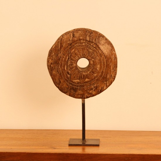 Antique Wooden Wheel Decor Genuine antique wooden wheel with a hand-carved radiating floral pattern around a central hole, mounted upright on a stand as a tabletop decor piece.
