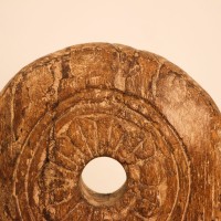 Antique Wooden Wheel Decor Genuine antique wooden wheel with a hand-carved radiating floral pattern around a central hole, mounted upright on a stand as a tabletop decor piece.