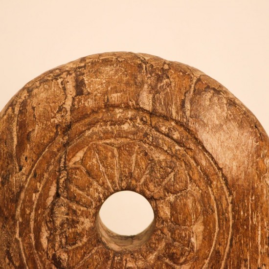 Antique Wooden Wheel Decor Genuine antique wooden wheel with a hand-carved radiating floral pattern around a central hole, mounted upright on a stand as a tabletop decor piece.