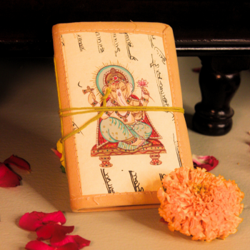 Handmade Ganesha Bahi Khata diary placed near pooja setup with marigold flowers and diya